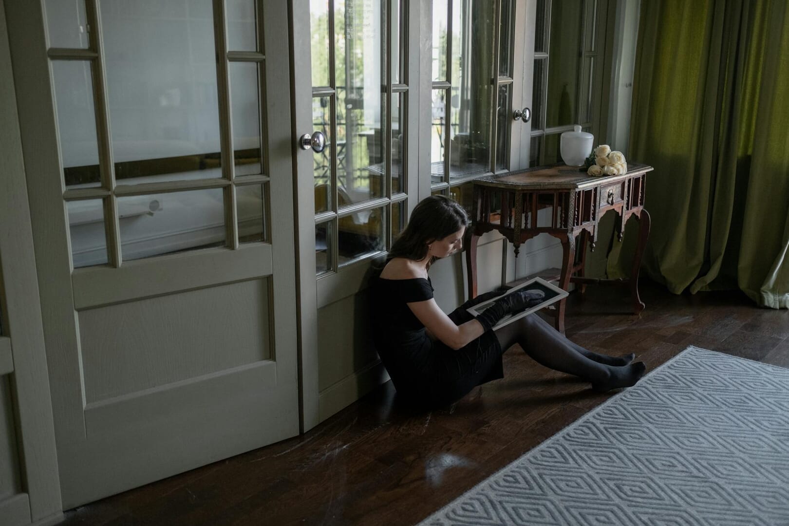 a woman sitting on the floor while looking at the picture