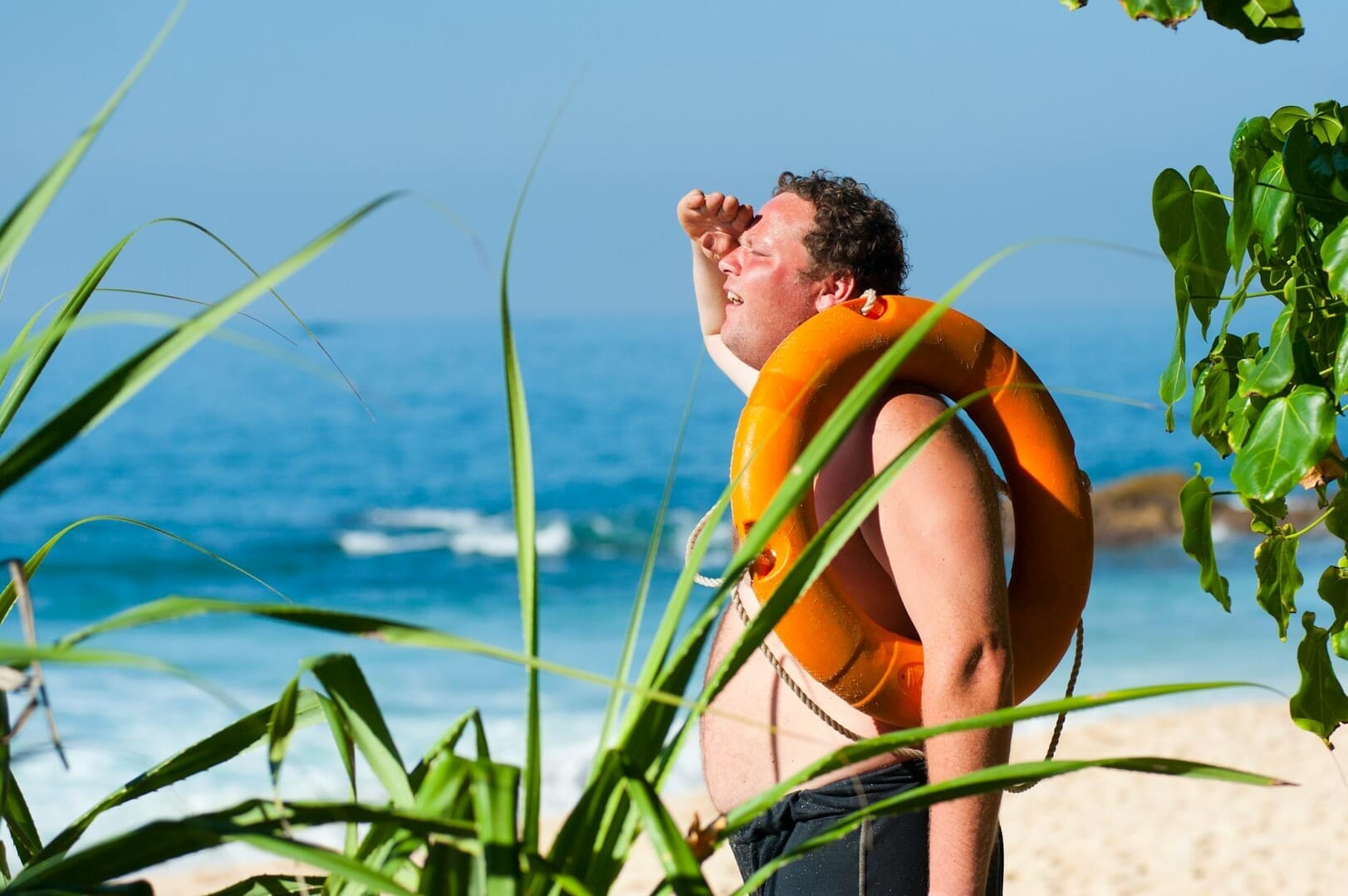 orange safety ring on man shoulder near body of water